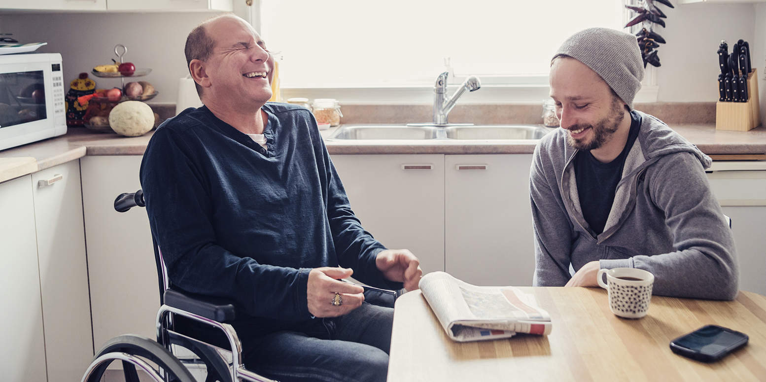a man in a wheelchair laughing with a young man